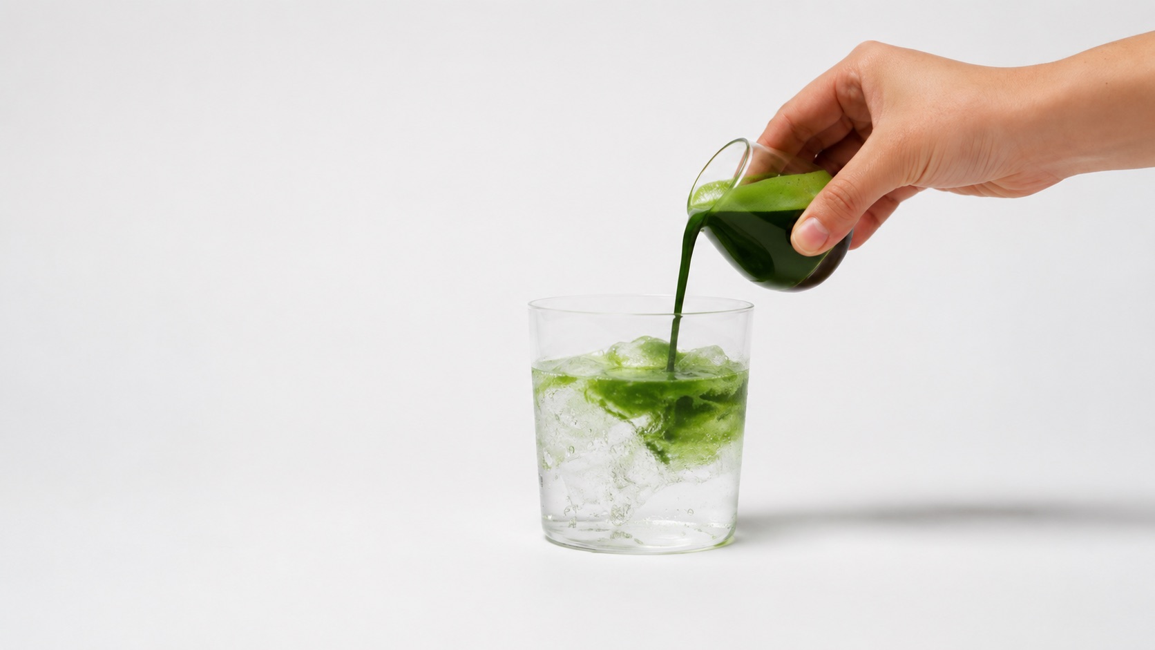 Nudo Matcha wird aus einer Karaffe in ein Glas mit Eis gegossen